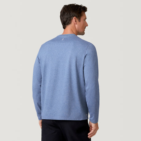 A man with short brown hair stands with his back to the camera against a light background, wearing a Free Country Men's FreeCycle® Sueded Melange Long Sleeve Crew Neck in light blue and black pants.