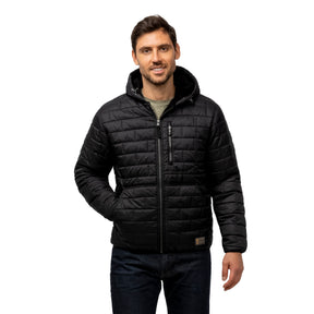 A man stands facing forward, smiling, wearing the Clearance Men's FreeCycle® Brick Puffer+ Jacket in black with a hood and front zipper, paired with dark jeans. His left hand is in his pocket; his right arm rests by his side against a white background.