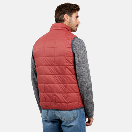 [Justin is 6'1" wearing a size Medium.] Man wearing the Free Country Men's FreeCycle® Stimson Puffer Vest in red, featuring quilted design, REPREVE® poly fill, and a vertical zip, layered over a grey long-sleeve shirt with light jeans.