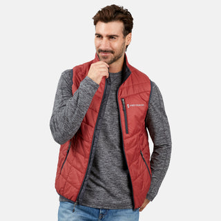 [Justin is 6'1" wearing a size Medium.] Man wearing the Free Country Men's FreeCycle® Stimson Puffer Vest in red, featuring quilted design, REPREVE® poly fill, and a vertical zip, layered over a grey long-sleeve shirt with light jeans.