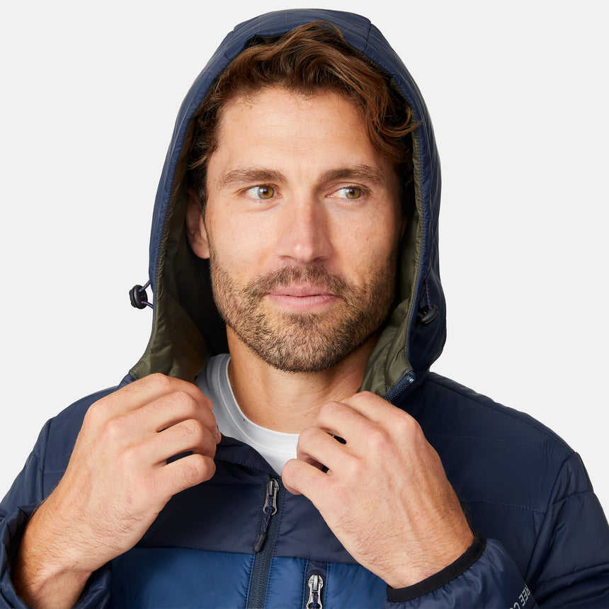 [Matt is 6'2" wearing size M.] Men’s Free Country zip-front puffer jacket in navy with multicolored horizontal chest stripes—featuring full-length zipper closure, insulated design, and classic hood-free silhouette. Paired with a white shirt and blue jeans for a vibrant, cold-weather look with retro-inspired flair.