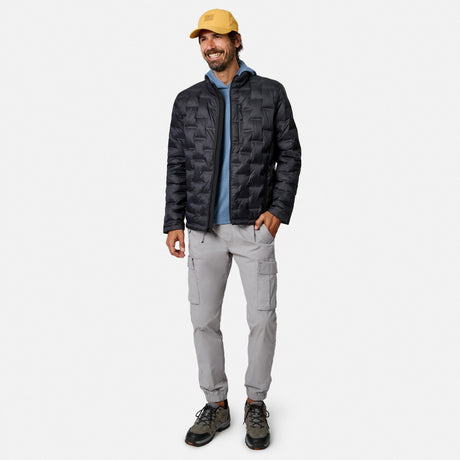 [Model is wearing size M.] A man wearing a black patterned puffer jacket, a blue hoodie, light gray cargo pants, and a yellow cap, standing against a light gray studio background.