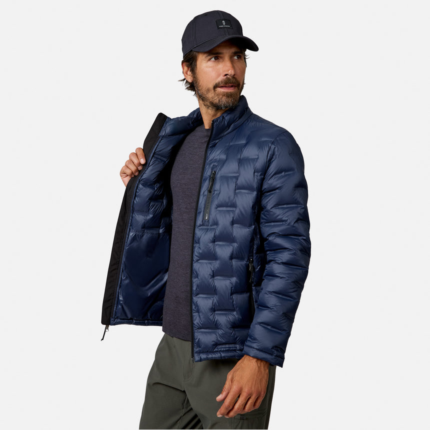 [Model is wearing size M.] A man wearing a navy blue puffer jacket over a dark gray shirt, olive green pants, and a black baseball cap, standing against a light gray studio background.