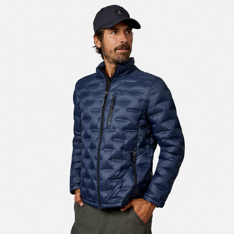 [Model is wearing size M.] A man wearing a navy blue puffer jacket, a dark navy baseball cap, and gray pants, standing against a light gray studio background.