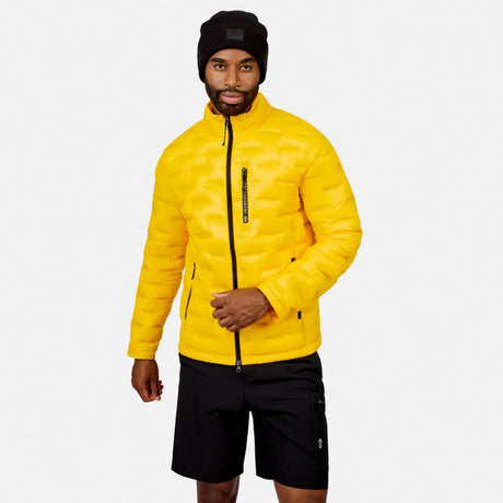 [Model is wearing size M.] A man wearing a bright yellow quilted puffer jacket with black zippers, a black beanie, and black shorts, standing against a light gray studio background.