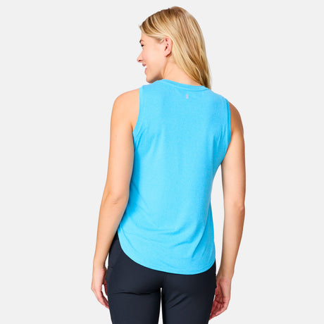 A woman with long blonde hair smiles over her shoulder, wearing the Clearance Women's Microtech® Chill B Cool Curved Hem Tank Top in bright blue and black leggings, enjoying all-day comfort and UPF 50+ protection against a plain light background.