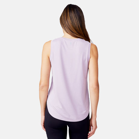 A woman with straight, light brown hair models the Women's Microtech® Chill B Cool Curved Hem Tank Top from Clearance in light purple, paired with black leggings, standing with her back to the camera against a white background.