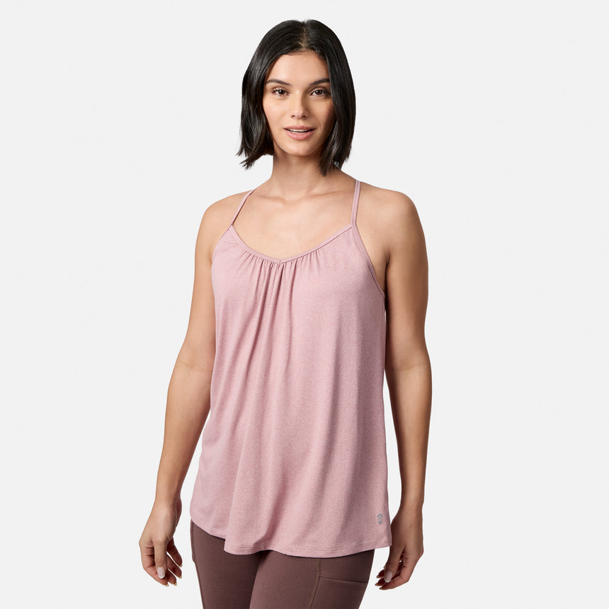A woman with short dark hair wears a light pink sleeveless top and mauve Free Country Women’s Trail 2 Town Flare Pants, standing against a plain white background.