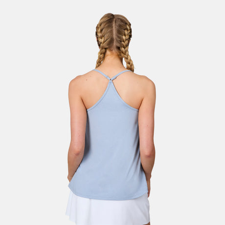 A woman with blonde braided hair is seen from the back wearing a light blue Free Country Women's Microtech® Chill B Cool V-Neck Cami Top with Built-In Bra and a white skirt, standing against a plain white background.