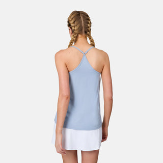 A woman with blonde braided hair stands with her back to the camera, wearing a Free Country Women's Microtech® Chill B Cool V-Neck Cami Top with Built-In Bra in light blue and a white skirt, set against a plain white background.
