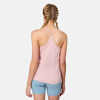 A woman with blonde braided hair stands with her back to the camera, wearing a light pink Free Country Women's Microtech® Chill B Cool V-Neck Cami Top with Built-In Bra and light blue shorts against a plain white background.