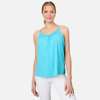 A woman smiles wearing the Free Country Women's Microtech® Chill B Cool V-Neck Cami Top with Built-In Bra in light blue and white pants, standing against a plain white background.