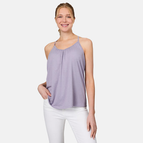 A woman wearing the Free Country Women's Microtech® Chill B Cool V-Neck Cami Top with Built-In Bra in light purple and white pants stands against a white background, smiling with one hand in her pocket.