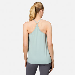 A blonde woman in a ponytail, seen from behind, models the Free Country Women's Microtech® Chill B Cool V-Neck Cami Top with Built-In Bra in light blue and gray leggings against a plain white background.