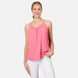 A woman smiles with one hand in her pocket, wearing the Free Country Women's Microtech® Chill B Cool V-Neck Cami Top with Built-In Bra in pink and white pants, standing against a plain white background.