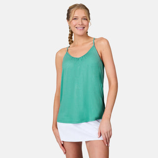 A woman with braided hair smiles while wearing the Free Country Women's Microtech® Chill B Cool V-Neck Cami Top with Built-In Bra in green and a white skirt, standing against a plain white background.