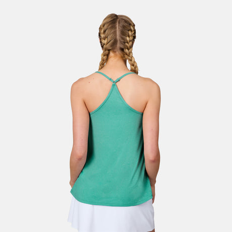 A woman with blonde hair in two braids wears a green Free Country Women's Microtech® Chill B Cool V-Neck Cami Top with Built-In Bra and a white skirt, facing away from the camera against a plain white background.