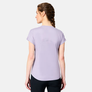 A woman with braided hair, seen from behind, wears the Free Country Women's Microtech® Chill B Cool Tee in light purple and black pants against a plain light gray background.