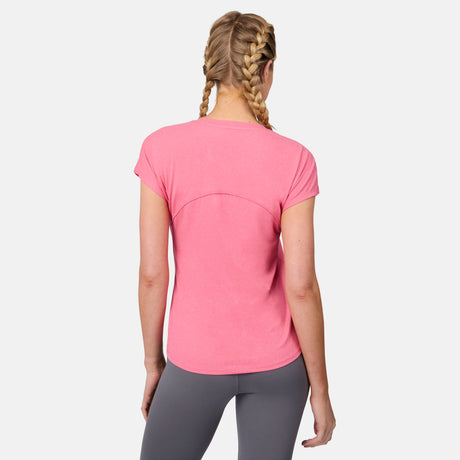 A woman with blonde braided hair wears the Free Country Women's Microtech® Chill B Cool Tee in pink and gray leggings, standing with her back to the camera against a plain white background.