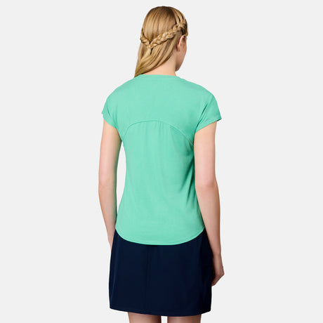 A woman with blonde hair in a braid stands with her back to the camera, wearing the Free Country Women's Microtech® Chill B Cool Tee in light green and a dark navy skirt, against a plain white background.
