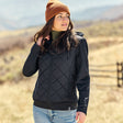 Woman wearing a black quilted jacket and brown beanie in an outdoor setting