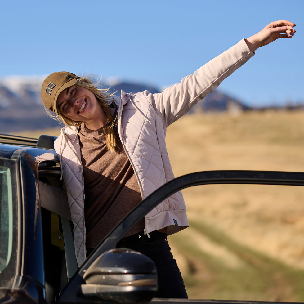 Woman leaning out of a car window with mountains in the background