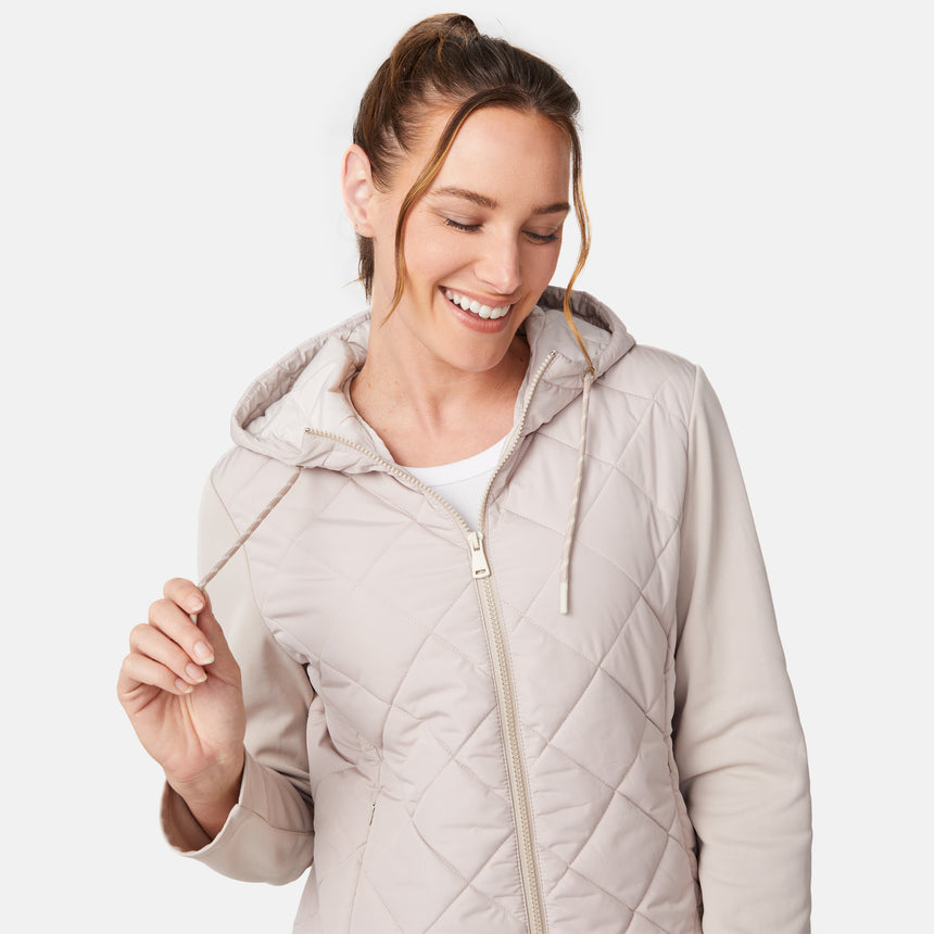 [Emily is 5'9" wearing size S.] Women’s light-colored quilted jacket with diamond-pattern stitching, zip-front closure, hood, and zippered pockets—layered over a white long-sleeve shirt and styled with black pants for a casual, cool-weather look.