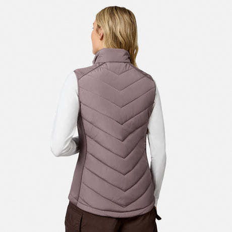 Back view of a person wearing a lightweight, mauve Women’s Quilted Hybrid Vest by Free Country over a long-sleeved white shirt.