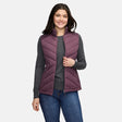 A woman wears a plum-colored Free Country Women’s Quilted Hybrid Vest with REPREVE synthetic fill over a grey long-sleeved shirt and blue jeans.