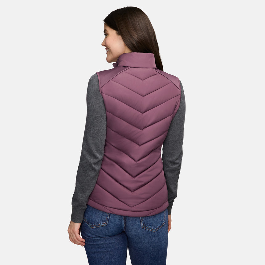 A person seen from the back wearing a purple Free Country Women’s Quilted Hybrid Vest with REPREVE synthetic fill over a grey long-sleeved shirt and blue jeans.