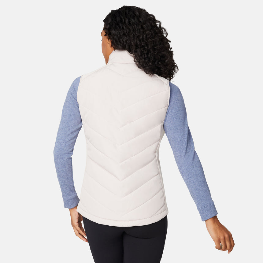 [Angelique is 5'10" wearing size S.] Woman wearing a beige puffer vest over a blue long-sleeve shirt on a white background
