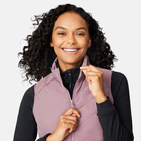 [Angelique is 5'10" wearing size S.] Woman wearing a purple quilted vest over a black long-sleeve shirt on a white background
