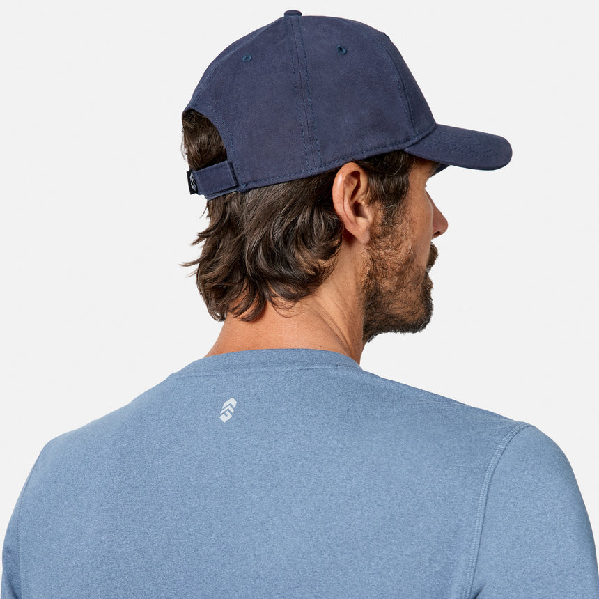 [Model is wearing size M.] A man shown from the back wearing a navy blue baseball cap and a heathered blue t-shirt, photographed against a clean white background.
