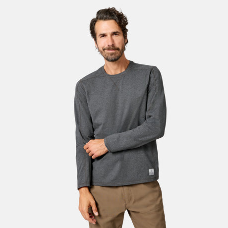 [Model is wearing size M.] A man wearing a dark gray long-sleeve crewneck sweatshirt and tan pants, standing against a light gray studio background.