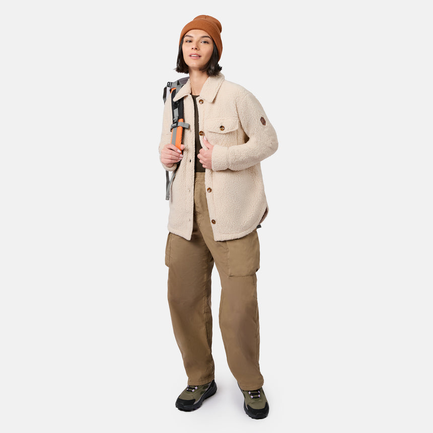 [Model is wearing size S.] A model stands against a light gray studio background wearing a cream textured button-up jacket, brown cargo pants, a rust-orange beanie, and hiking boots, with a backpack visible over one shoulder.