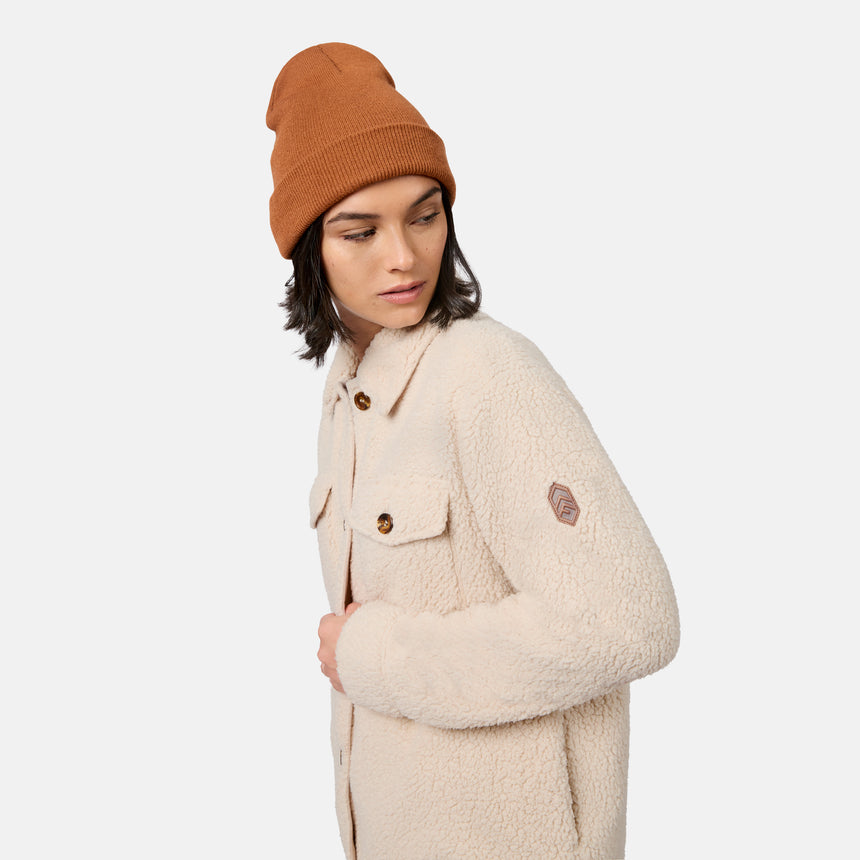 [Model is wearing size S.] A model wearing a warm beige sherpa fleece button-up jacket with brown buttons and a small brown shield logo on the sleeve, paired with a rust-orange knit beanie, set against a plain light gray background.