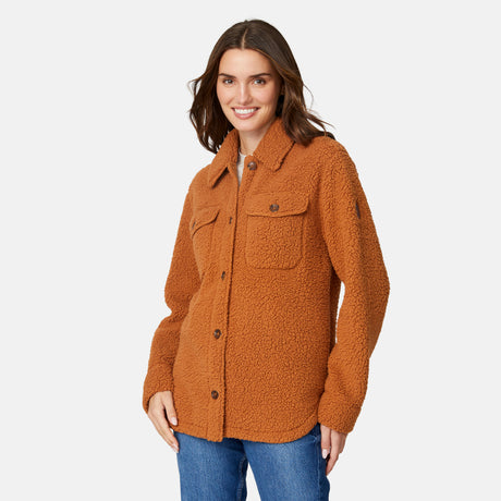 A woman with brown hair models the Free Country Women's Sherpa Shacket—an oversized, super-soft layer with buttons and front pockets—paired with blue jeans against a plain white background.