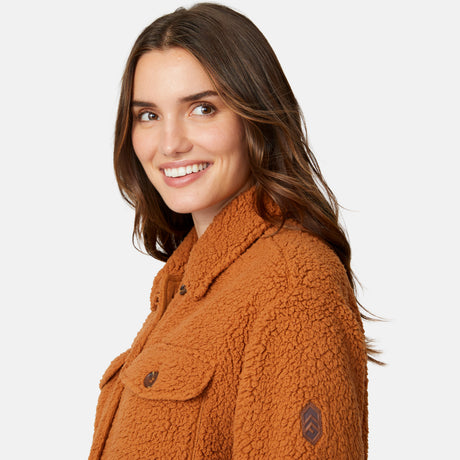 A woman with long brown hair smiles over her shoulder wearing the super-soft Free Country Women's Sherpa Shacket, set against a plain light background.