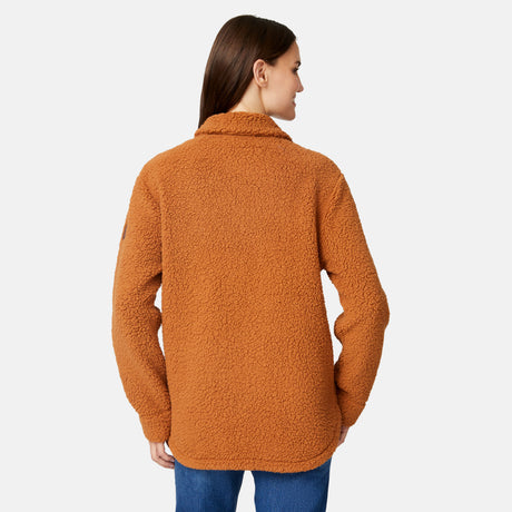 A woman with long brown hair wears the Free Country Women's Sherpa Shacket in an oversized fit and blue jeans, standing with her back to the camera against a plain light background.