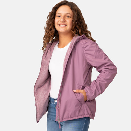 A smiling young girl with curly hair wears the Clearance Girls' Windshear Jacket—wind and water resistant—in light purple over a white shirt and blue jeans, with one hand in her pocket against a plain light background.