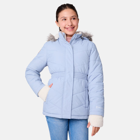 [Samantha is wearing size M] Model wearing a light blue Free Country winter jacket with faux fur-trimmed hood, quilted body, and white fleece-lined cuffs; styled with blue jeans for a casual, cold-weather look.