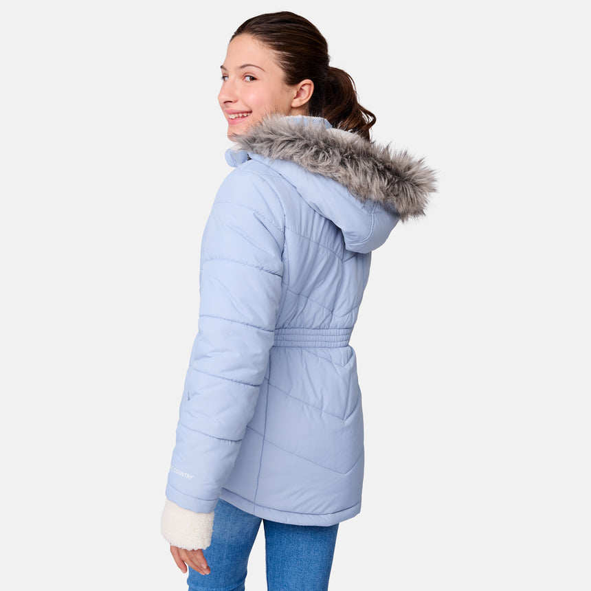 [Samantha is wearing size M] Model wearing a light blue Free Country winter jacket with faux fur-trimmed hood, quilted body, and white fleece-lined cuffs; styled with blue jeans for a casual, cold-weather look.