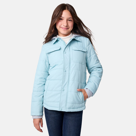 [Samantha is wearing size M.] Model wearing a Free Country light blue quilted jacket with button-front closure, flap chest pockets, and side pockets—layered over a white shirt with dark blue jeans for a casual, cold-weather look.