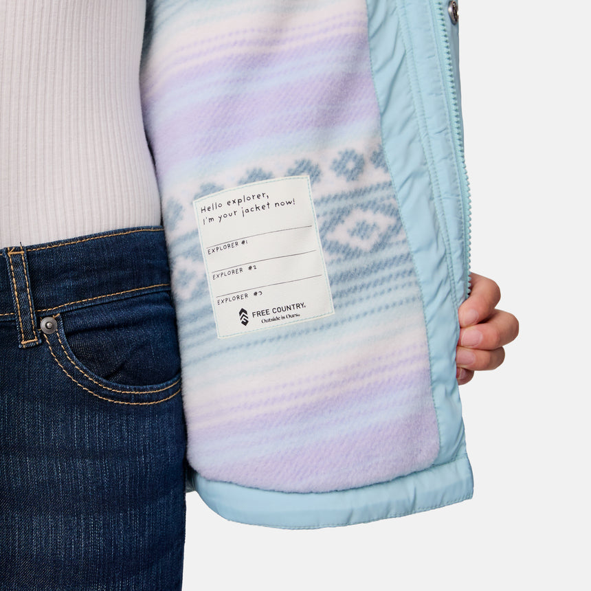 [Samantha is wearing size M.] Model wearing a Free Country light blue quilted jacket with button-front closure, flap chest pockets, and side pockets—layered over a white shirt with dark blue jeans for a casual, cold-weather look.