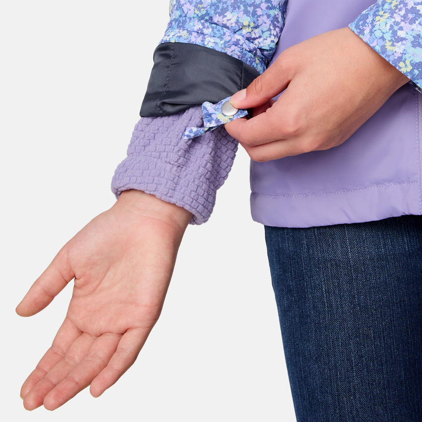 [Samantha is wearing size M.] Women's Free Country softshell jacket with floral upper print and solid lavender lower panels, featuring a zip-front closure and soft purple inner lining—designed for lightweight warmth and outdoor versatility.