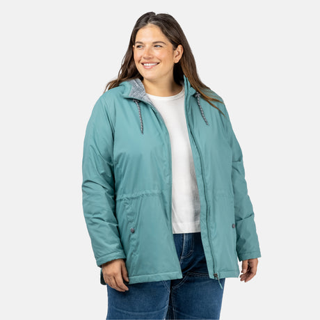 [Model is wearing a size 1X.] Woman wearing Free Country Women's Cascade Windshear Jacket in light blue with a full front zipper opening, soft lining, and water resistant and wind resistant recycled polyester stretch performance fabric, light grey background. Best women’s jacket for windy weather.