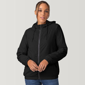 [Shelby is 5'9" wearing a size Small.] Woman wearing the Free Country Women's Breezy Bomber Windshear Jacket in black, featuring a hooded design and Iced Butter Pile® lining, standing casually with hands in pockets against a plain background.
