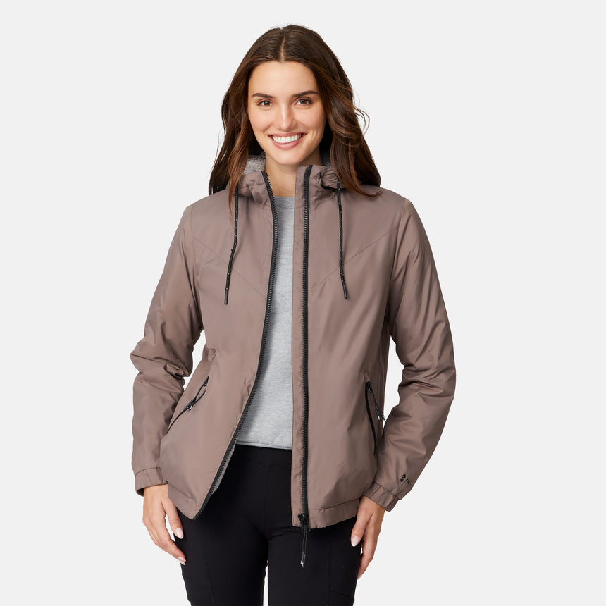 [Jessica is 5'9.5" wearing size S.] Free Country women’s light brown hooded jacket with black zippered pockets and drawstring hood—features plush sherpa lining for added insulation and comfort. Shown paired with black pants for a sleek, cold-weather outfit.