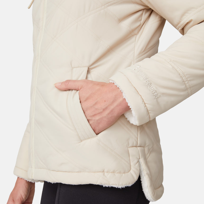 [Emily is 5'9" wearing size S.] Women’s Free Country cream-colored quilted hooded jacket with full-zip closure, drawstring hood, and dual hand pockets—reversible to cozy sherpa for versatile styling and added cold-weather comfort. Styled with jeans for a relaxed, outdoorsy look.