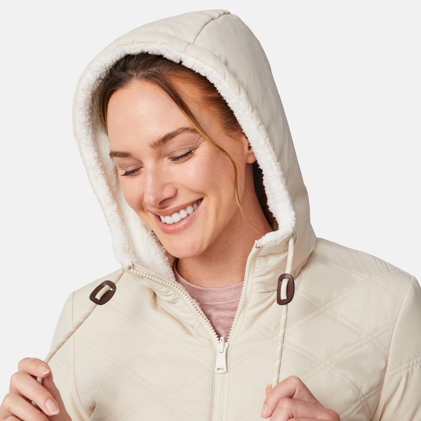 [Emily is 5'9" wearing size S.] Women’s Free Country cream-colored quilted hooded jacket with full-zip closure, drawstring hood, and dual hand pockets—reversible to cozy sherpa for versatile styling and added cold-weather comfort. Styled with jeans for a relaxed, outdoorsy look.